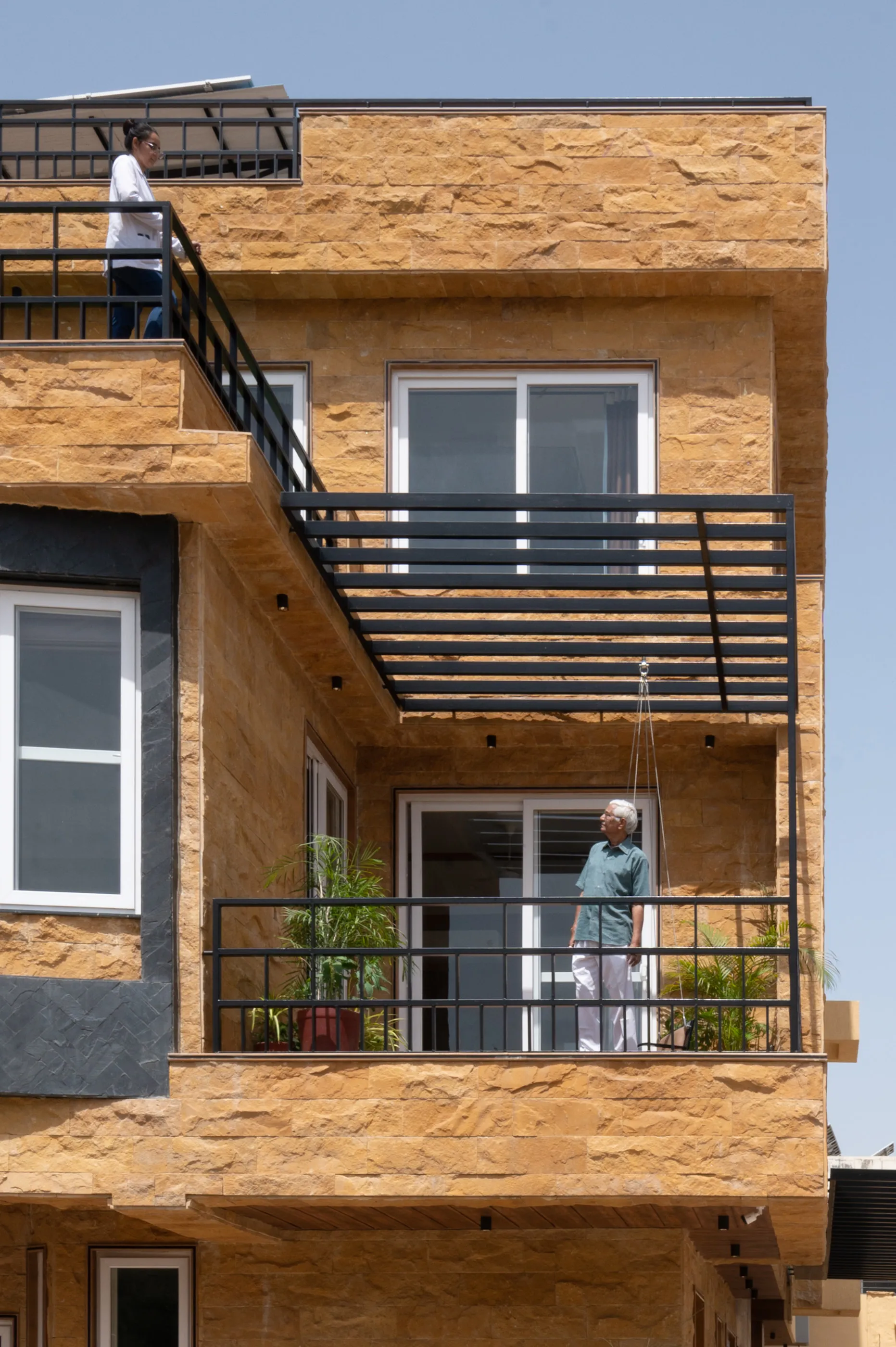 A stone-clad corner of the house with a black steel balcony