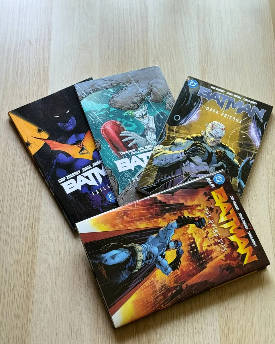 Four Batman graphic novels fanned out on a wooden table