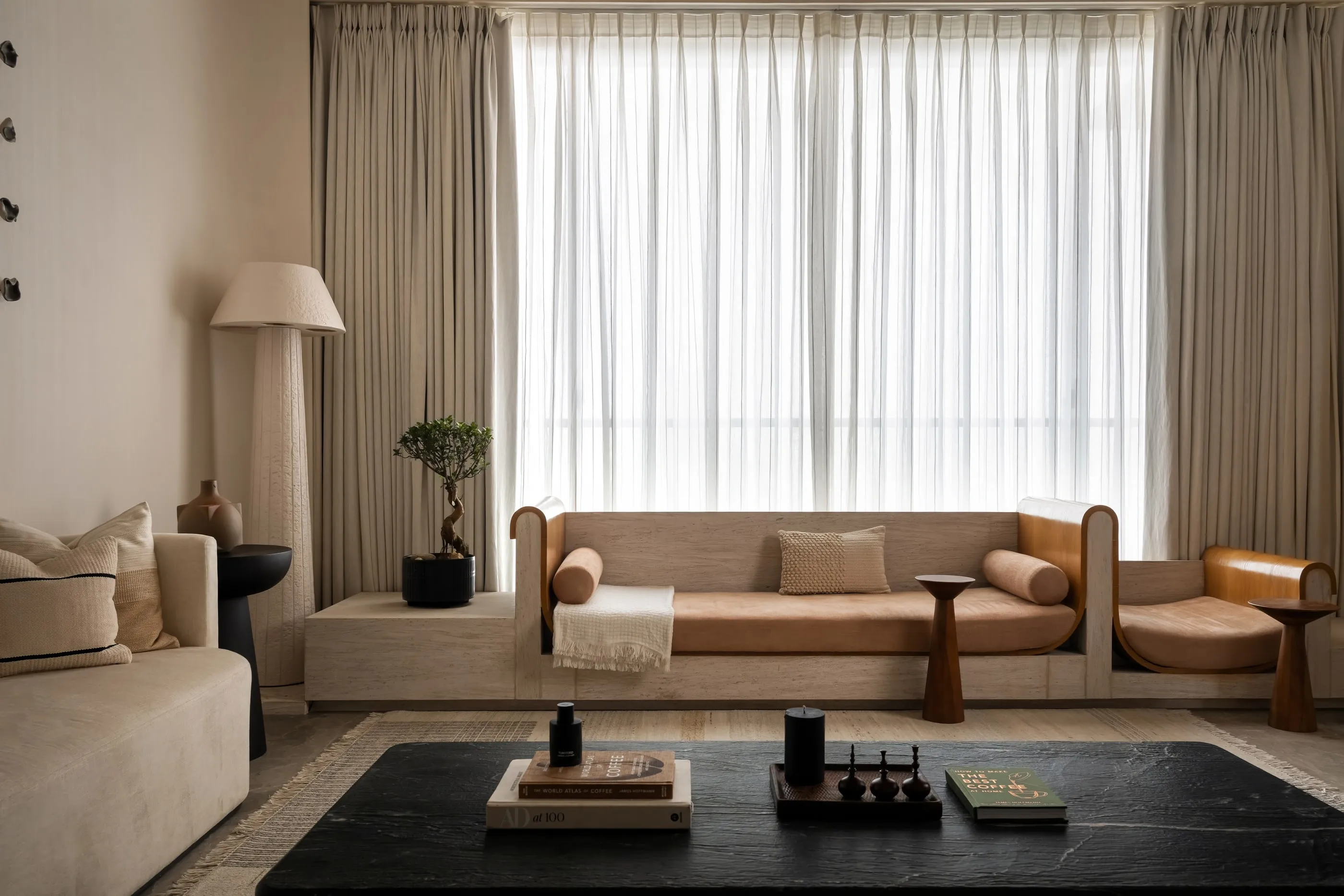 The Asara living room with a low sofa, dark coffee table and sheer curtains.