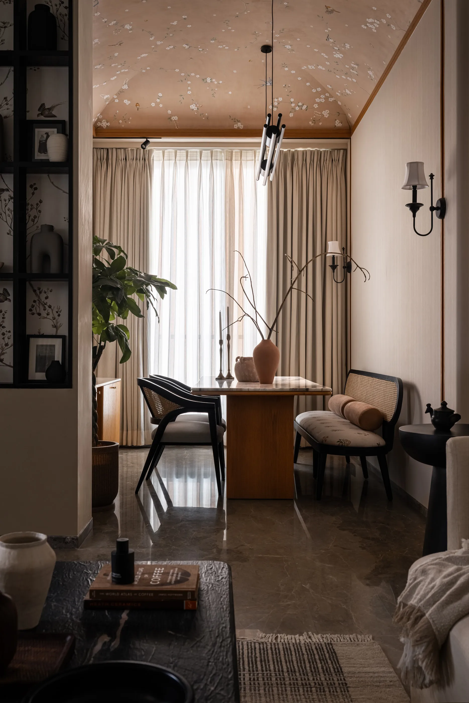 Built dining corner: marble-topped table with cane chairs and bench under a painted vault, sheer curtains behind