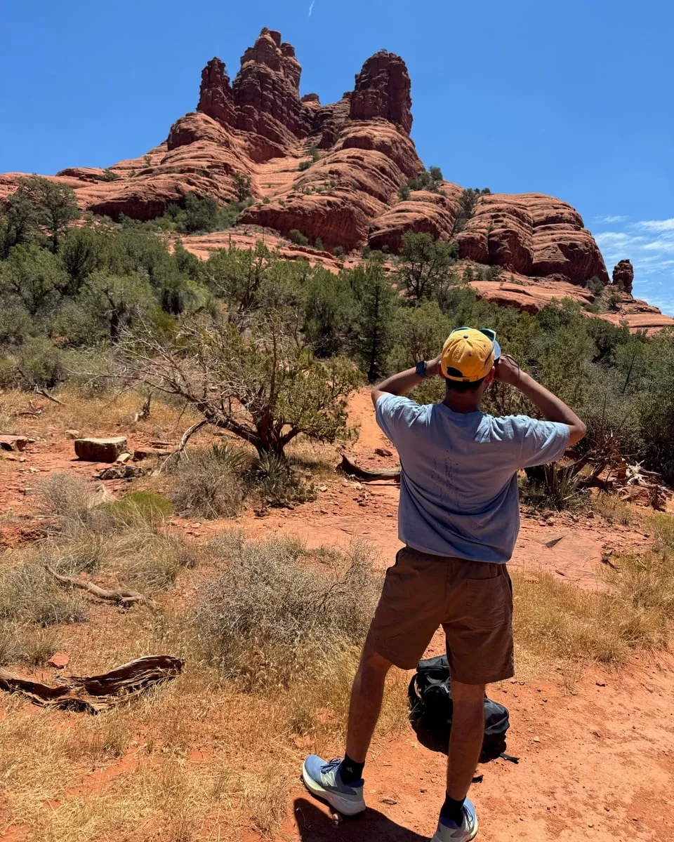 Archit on a desert trail, looking up at red rock spires